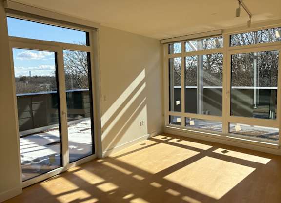 A sunny room with wooden floors and large windows. at 605 Concord at Fresh Pond Apartments, Cambridge, 02138