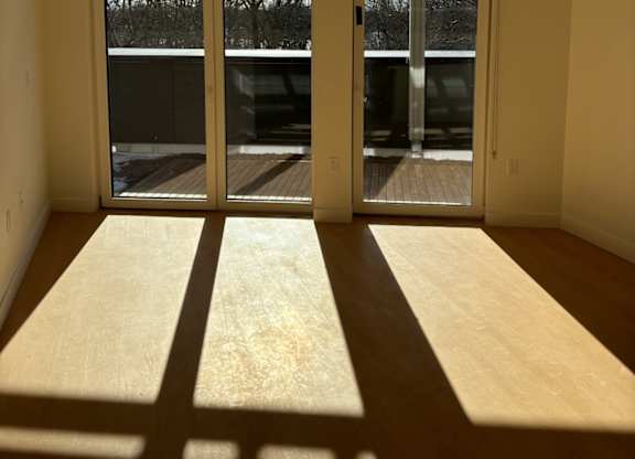 A room with a large sliding glass door that leads outside at 605 Concord at Fresh Pond Apartments, Cambridge, Massachusetts