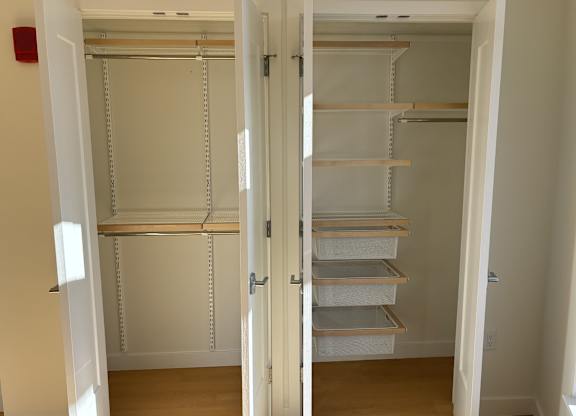 A white closet with shelves and drawers is open at 605 Concord at Fresh Pond Apartments, Massachusetts