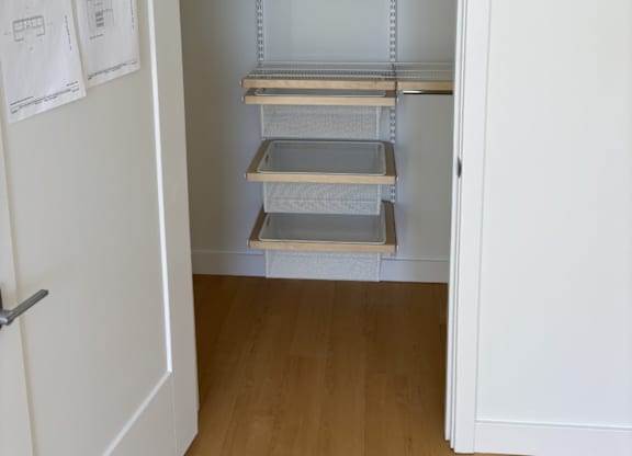 A white closet with shelves and a door at 605 Concord at Fresh Pond Apartments, Massachusetts