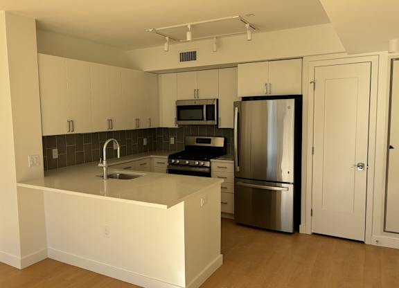A kitchen with a stainless steel refrigerator and a microwave above the stove at 605 Concord at Fresh Pond Apartments, Cambridge, Massachusetts