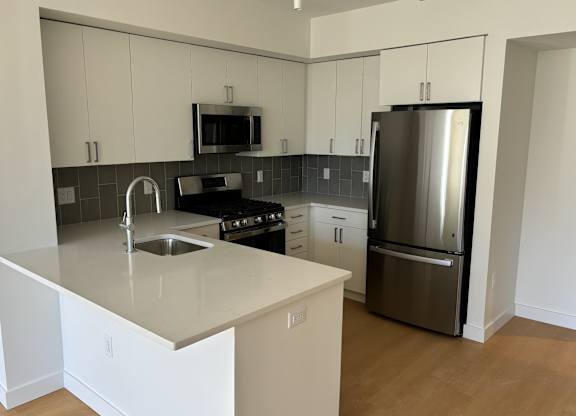 A kitchen with a stainless steel refrigerator and a white countertop at 605 Concord at Fresh Pond Apartments, Cambridge, MA