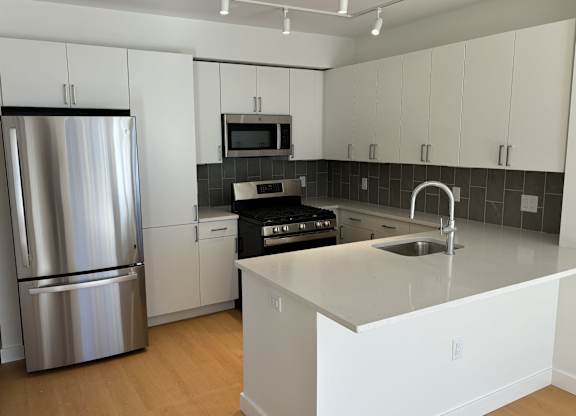 A modern kitchen with a stainless steel refrigerator and white cabinets. at 605 Concord at Fresh Pond Apartments, Massachusetts