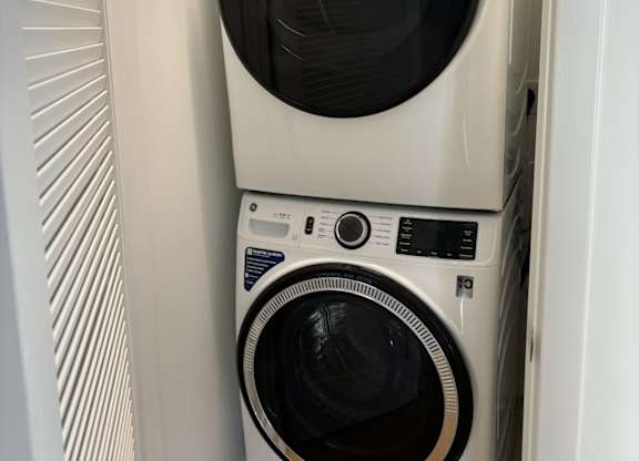 A white washing machine and dryer stacked on top of each other in a small space at 605 Concord at Fresh Pond Apartments, Cambridge, MA, 02138