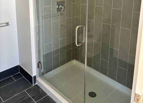 A glass shower stall with a door and a handle at 605 Concord at Fresh Pond Apartments, Cambridge
