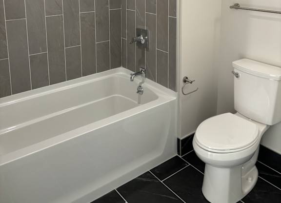 A white toilet sits next to a bathtub in a bathroom at 605 Concord at Fresh Pond Apartments, Massachusetts, 02138