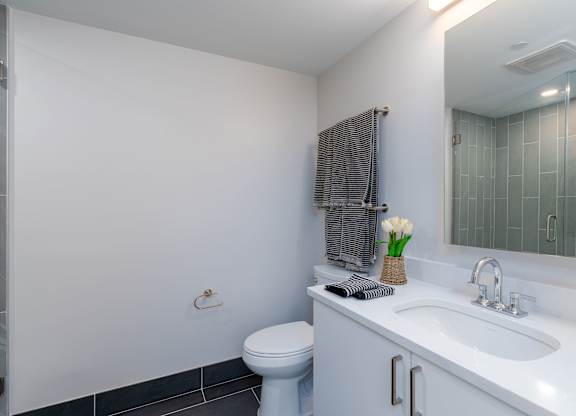A white bathroom with a toilet, sink, and shower at 605 Concord at Fresh Pond, Cambridge, MA