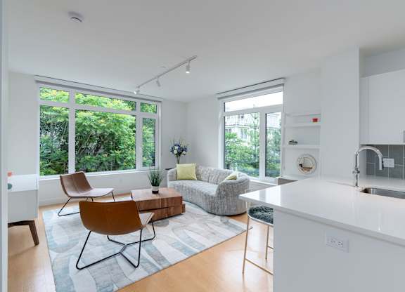A modern kitchen with white cabinets and a white island with quartz countertops at 605 Concord at Fresh Pond, Cambridge, 02138