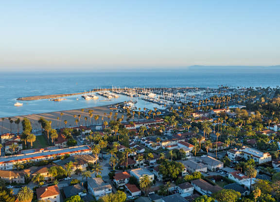 A coastal town with a pier and boats is seen from above.