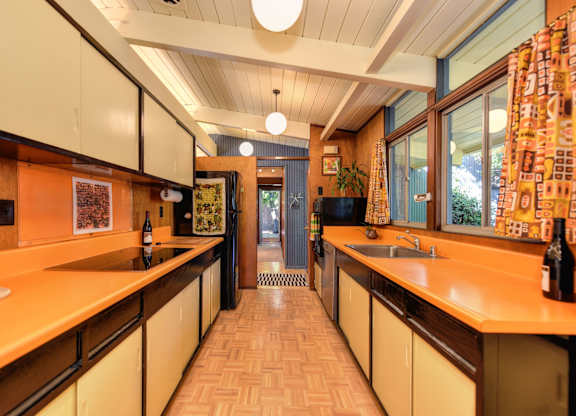 A kitchen with orange countertops and white cabinets.