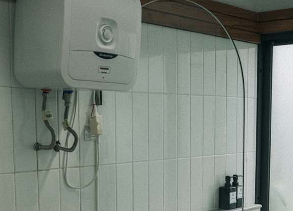 A white toilet is next to a white tiled wall.