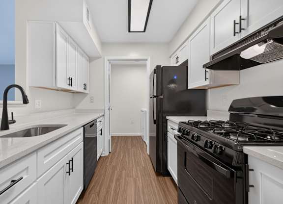 A kitchen with white cabinets and black appliances.