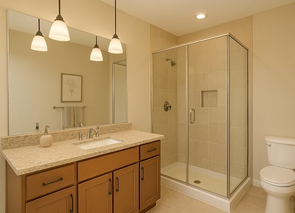 A bathroom with a sink, mirror, toilet and shower.
