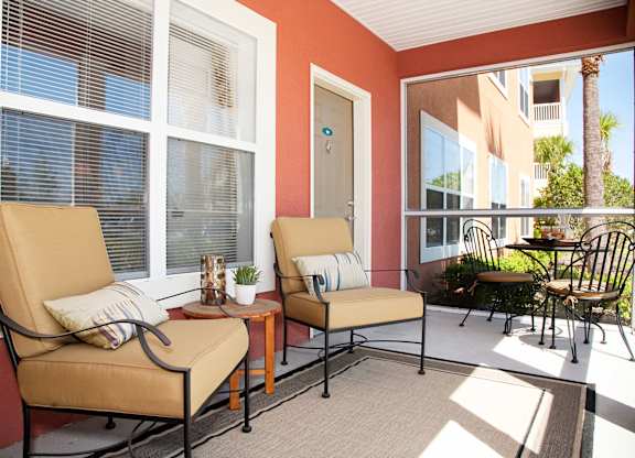 a porch with two chairs and a table and windows