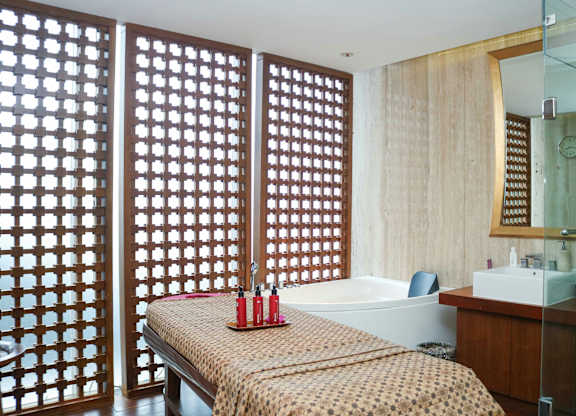 A bedroom with a bed, a bathtub, and a wooden screen.