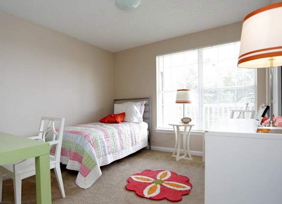 a bedroom with a bed and a desk and a window