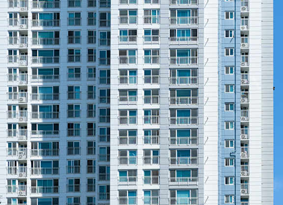 A tall building with many windows is shown against a blue sky.