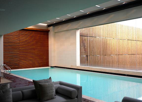 A modern indoor swimming pool with a glass wall.