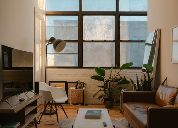 A living room with a brown couch, a white chair, a coffee table, and a large window.