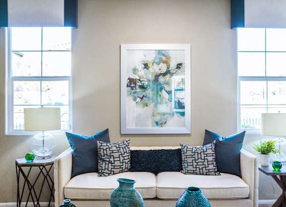 a living room with a couch and pillows and a painting on the wall