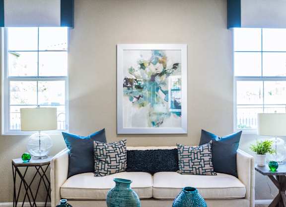 a living room with a couch and pillows and a painting on the wall