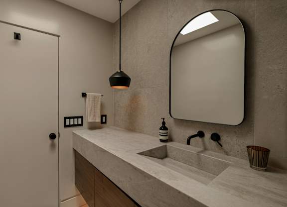 A bathroom with a sink, mirror, and a door.