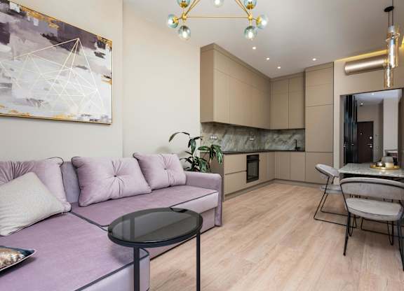 A modern living room with a purple couch and a black glass table.