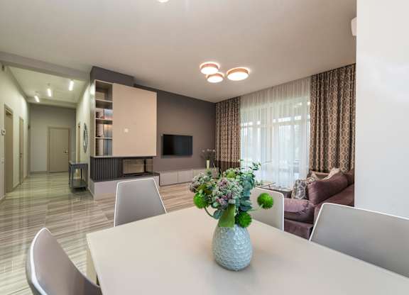 A dining room with a white table and chairs and a television in the corner.