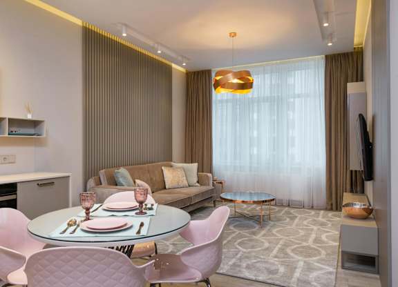 A modern dining room with a glass table and pink chairs.