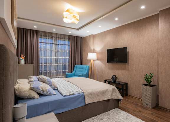 A bedroom with a large bed and a flat screen TV mounted on the wall.