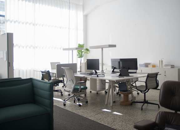 A modern office with a green chair and a desk with a laptop and a plant on it.