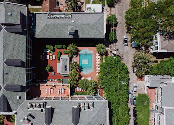 A modern building with a grey roof and a pool in the middle.