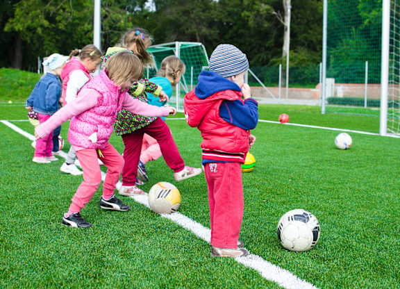 a group of young children kicking soccer balls on a field