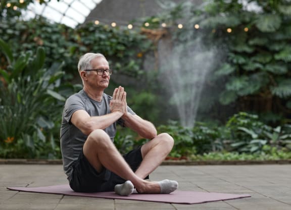 a man sitting on a yoga mat in front of a fountain