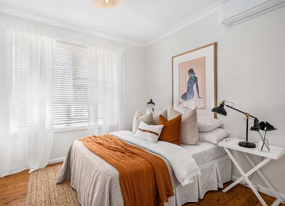 A bedroom with a bed, a nightstand, and a painting on the wall.