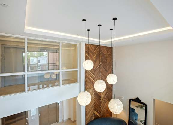 A modern interior with a wooden panel and hanging lights.