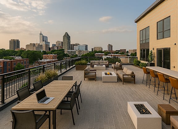 A patio with a laptop on a table overlooking a city skyline.