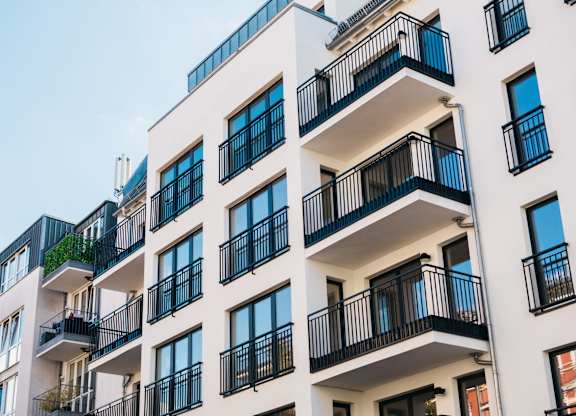 A white apartment building with black railings and balconies.