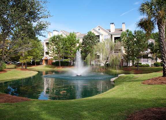 a fountain in the middle of a pond in front of a building