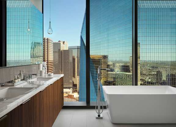 A modern bathroom with a large window overlooking a cityscape.