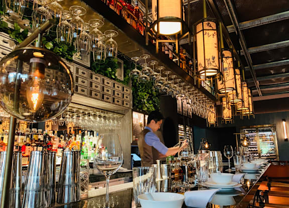 A bar with a person behind the counter and a lot of bottles.
