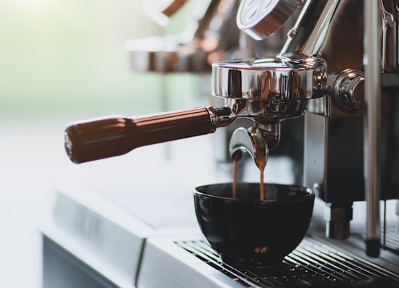 A coffee machine is dispensing coffee into a black cup.