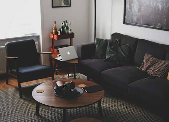 A living room with a black couch, a coffee table, and a chair.