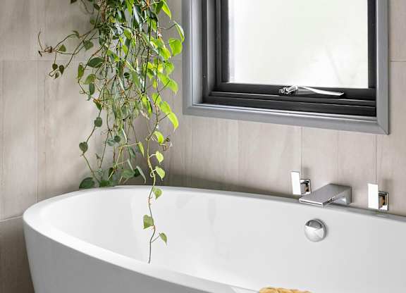 A white bathtub with a silver faucet and a mirror above it.