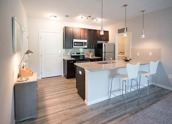 A kitchen with a bar area and white chairs.