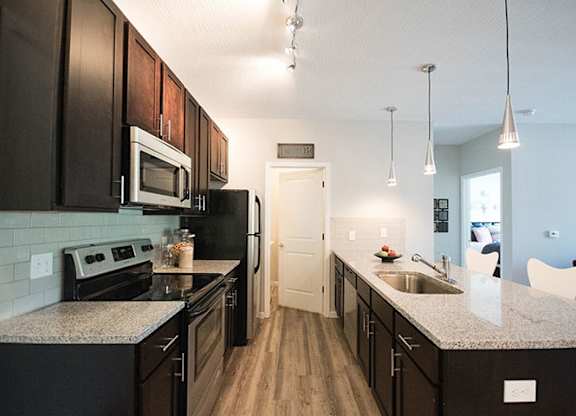 A kitchen with dark wood cabinets and granite countertops.