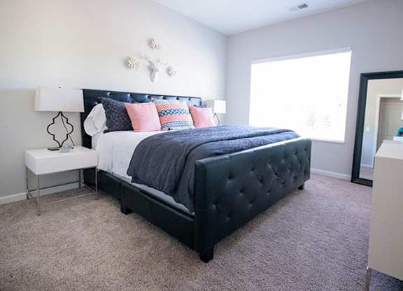 A bedroom with a large bed and a nightstand.