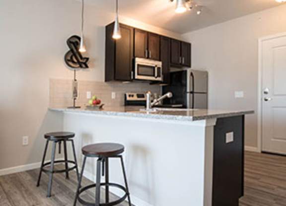 A kitchen with a white counter and two bar stools.