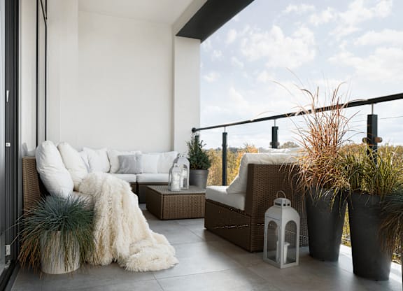 A white couch with a fur throw sits on a patio.