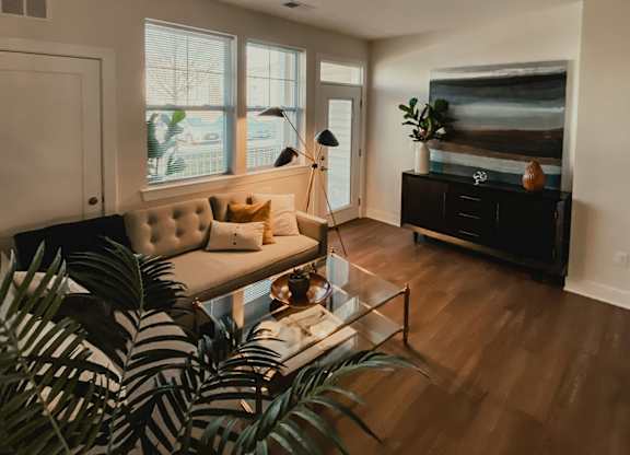 A living room with a white couch and a wooden floor.
